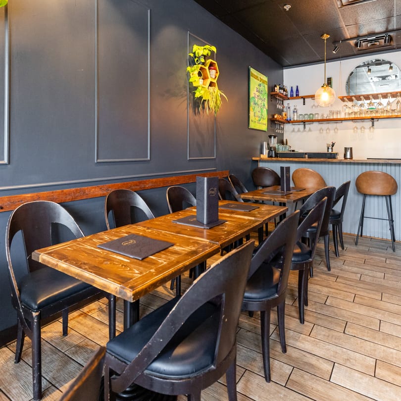 Interior of An Artistic Taste, showing dining tables with black chairs and a bar area with stools.